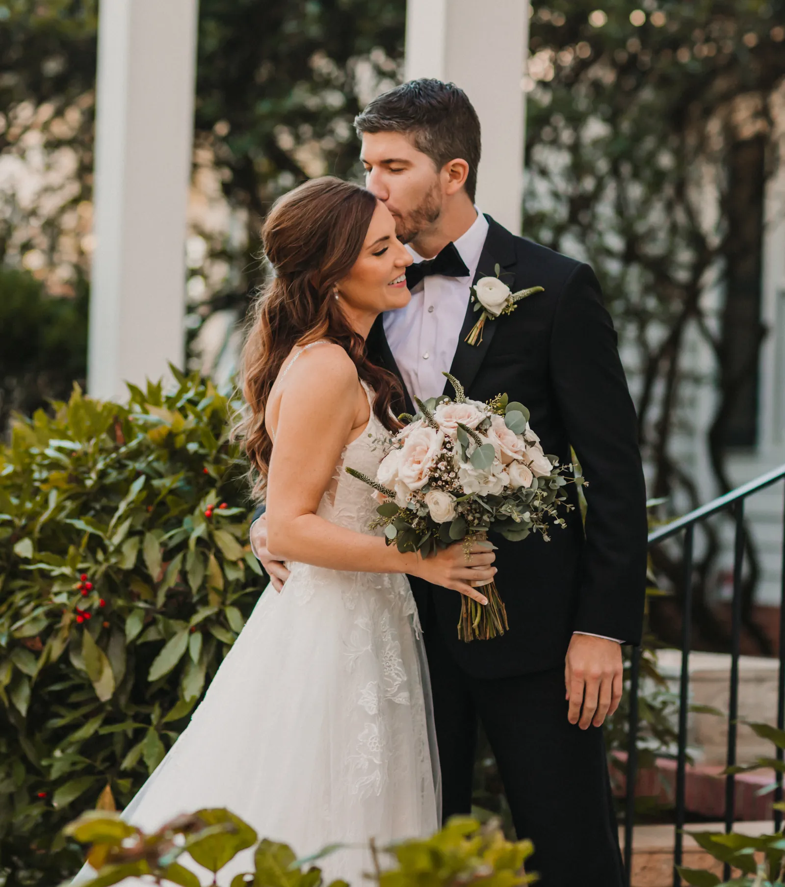 Daniel and Catherine on their wedding day, outside on the steps among the greenery